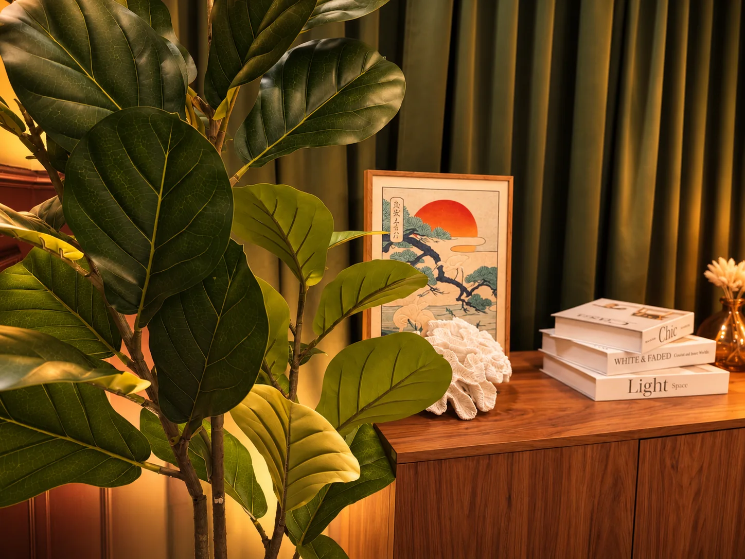 Leafy plants, framed artwork and books on the wooden studio sideboard